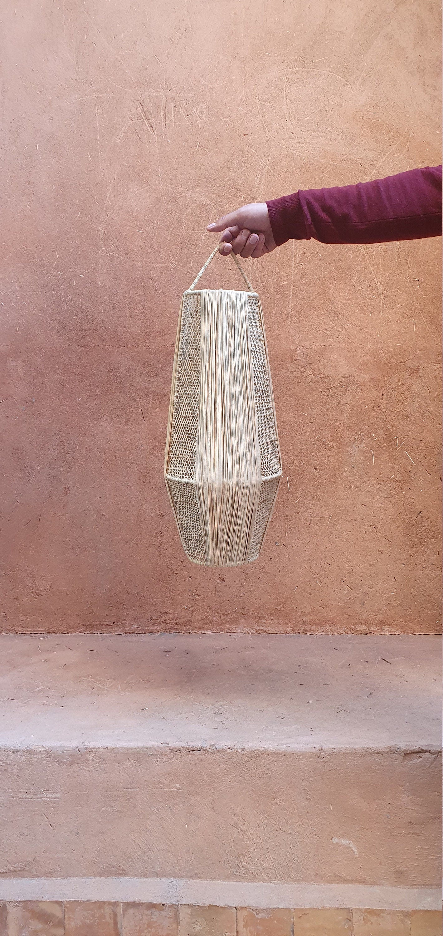 Lampe suspendue en raphia ornée d'une lanterne en dentelle.