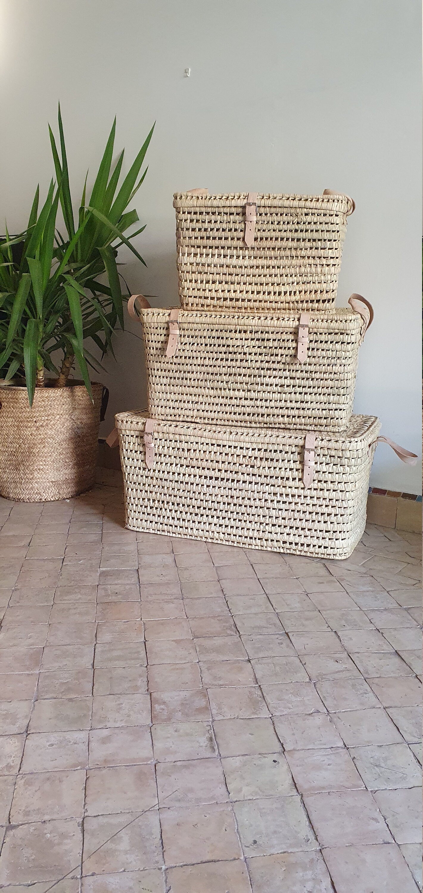 Vue rapprochée du coffre de rangement en feuilles de palmier, mettant en valeur ses détails tressés à la main et les anses en cuir.