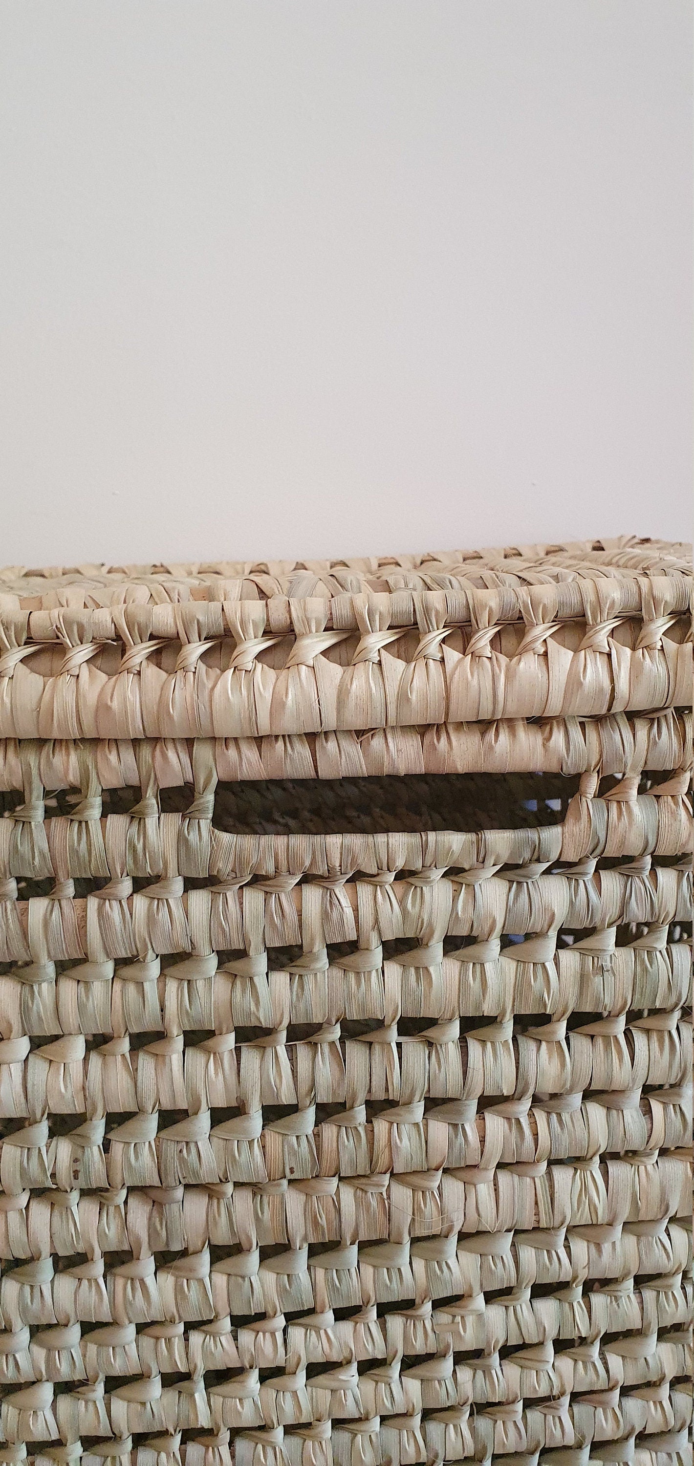 Ce panier en feuilles de palmier tressées offre une décoration bohème authentique pour votre intérieur.
