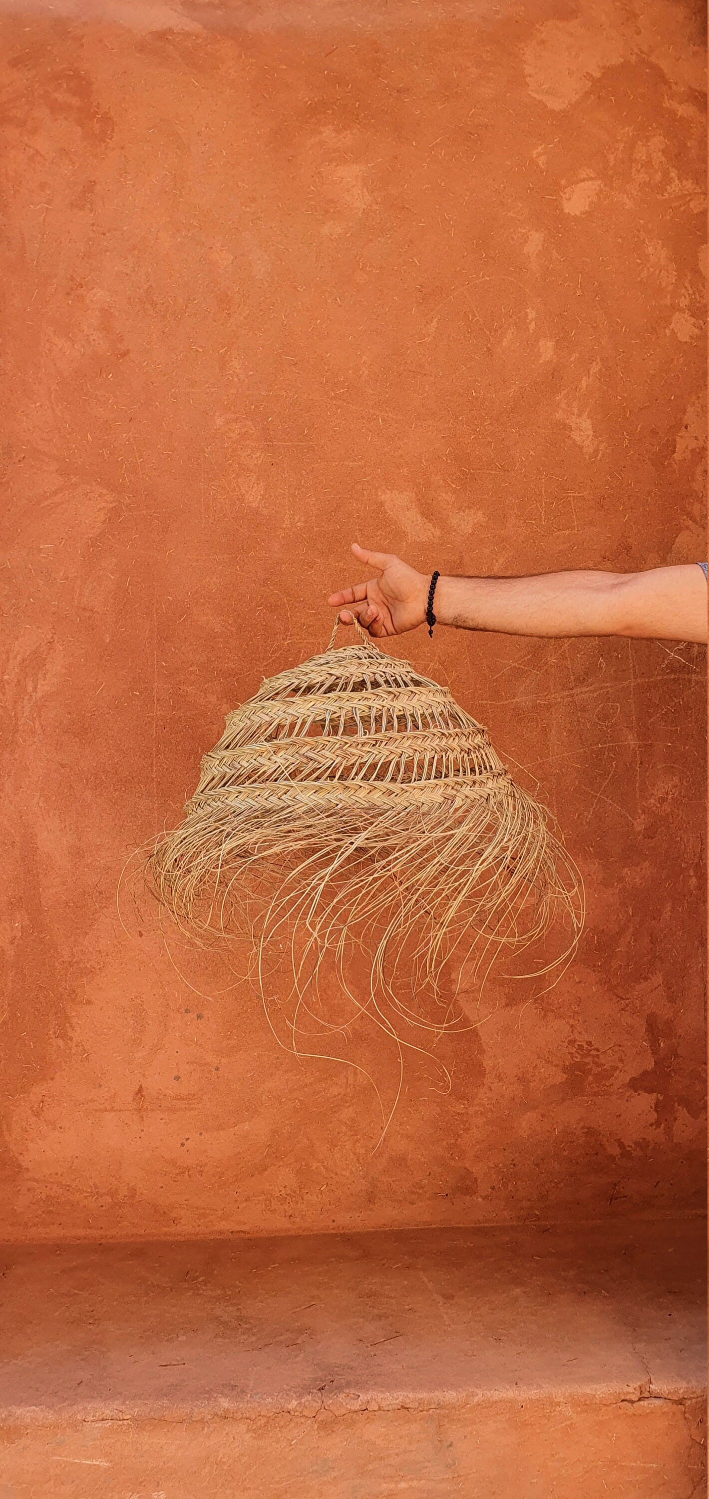 Suspension en forme de boule en doum et raphia avec éclairage naturel.