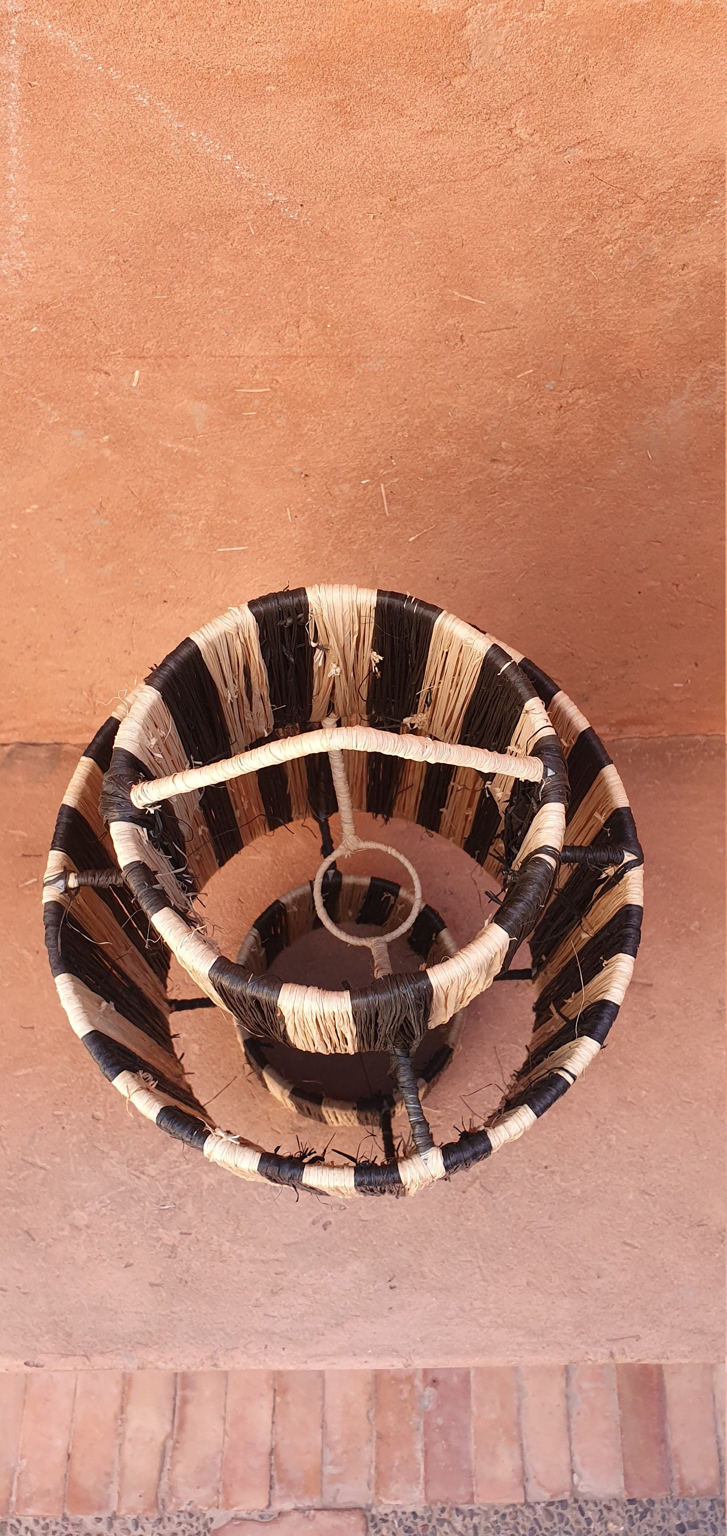 Suspension artisanale de 55 cm en osier et raphia, apportant une touche d'authenticité à votre décoration.