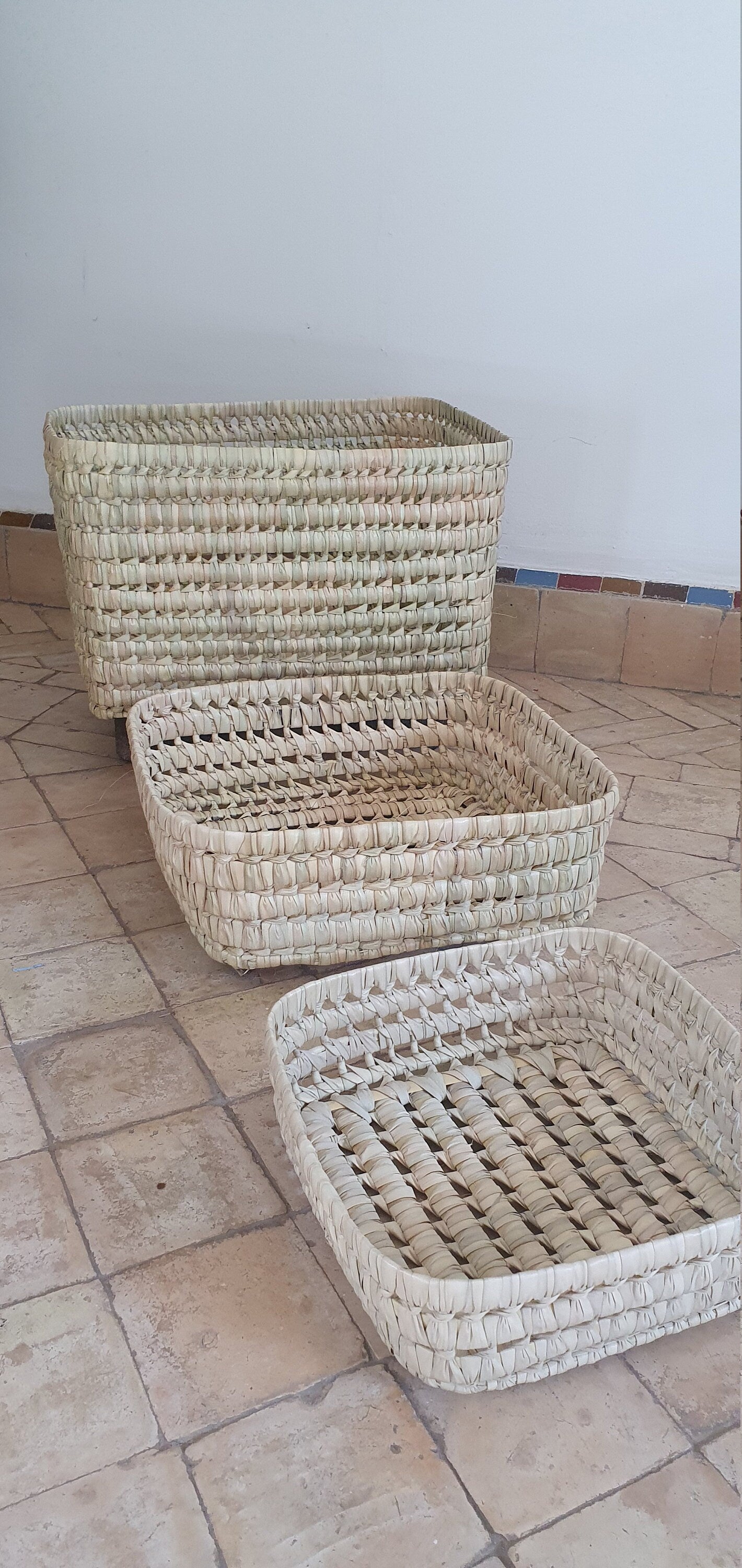 Panier de rangement en feuilles de palmier et osier, parfait pour ranger des coussins ou des couvertures.