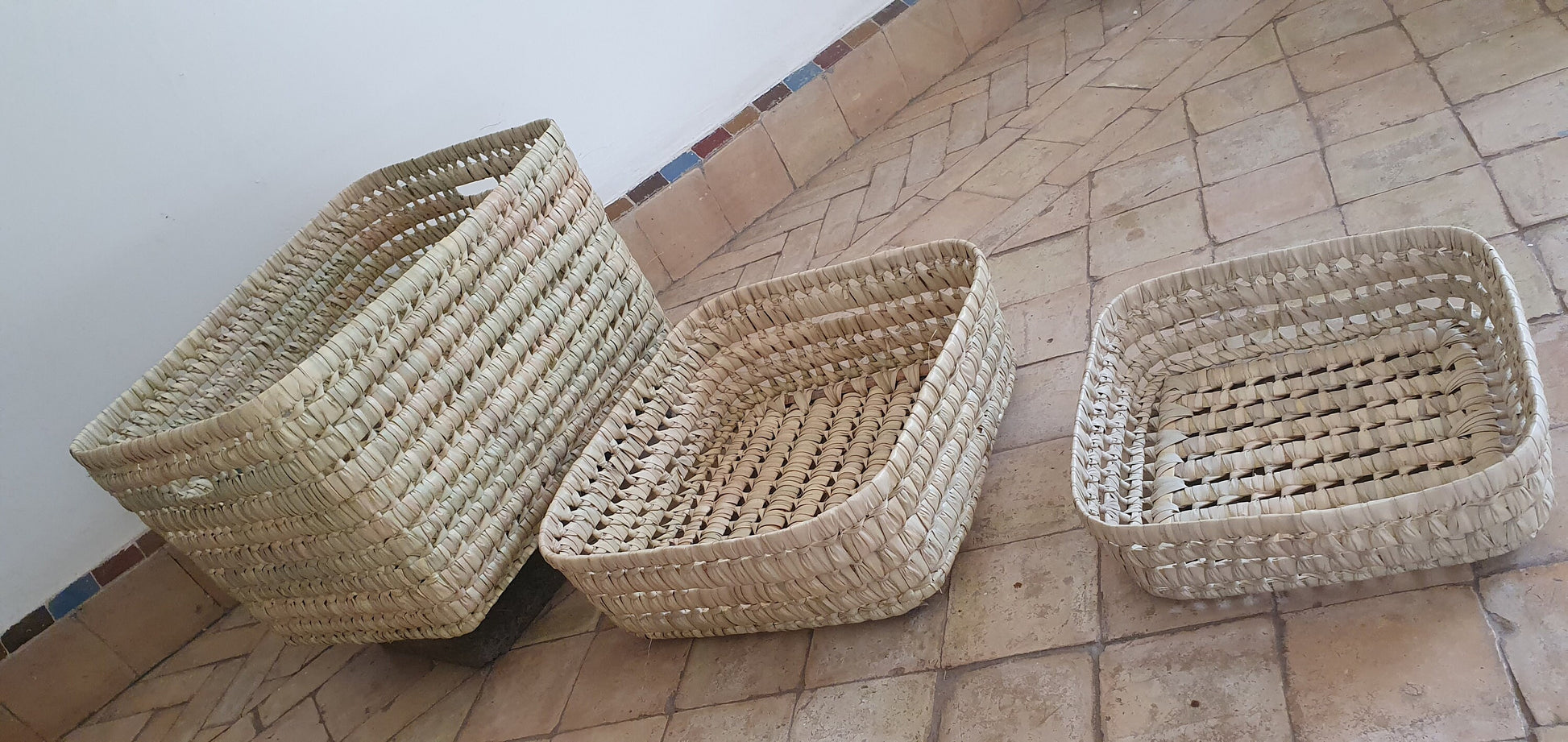 Un panier artisanal en feuilles de palmier et osier, ajoutant une touche d'exotisme à votre décoration intérieure.