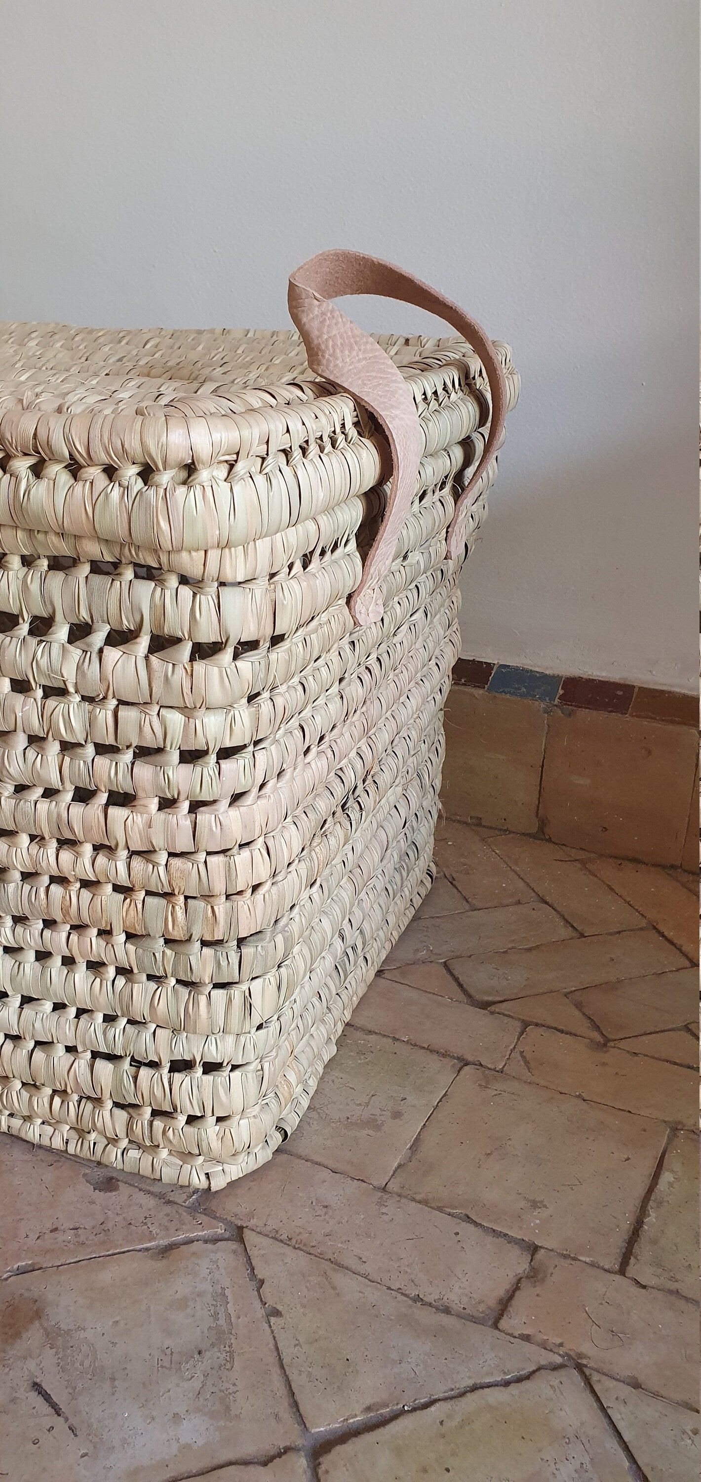 Coffre de rangement en feuilles de palmier avec anses en cuir, un accessoire de décoration intérieure artisanal