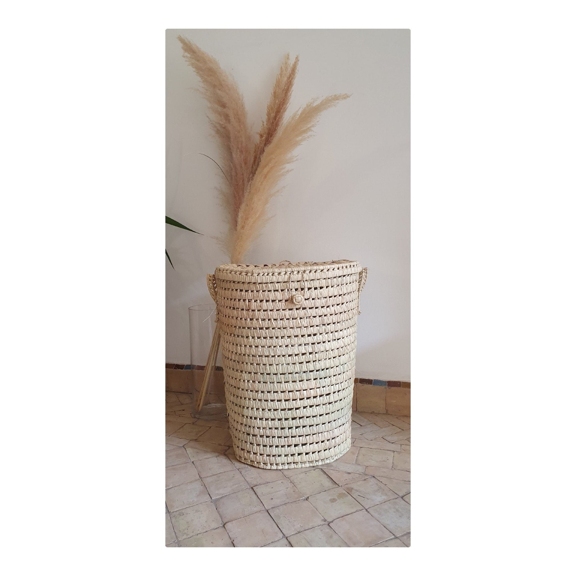 Un panier de rangement rond en feuilles de palmier, ajoutant une touche d'élégance naturelle à la décoration intérieure.