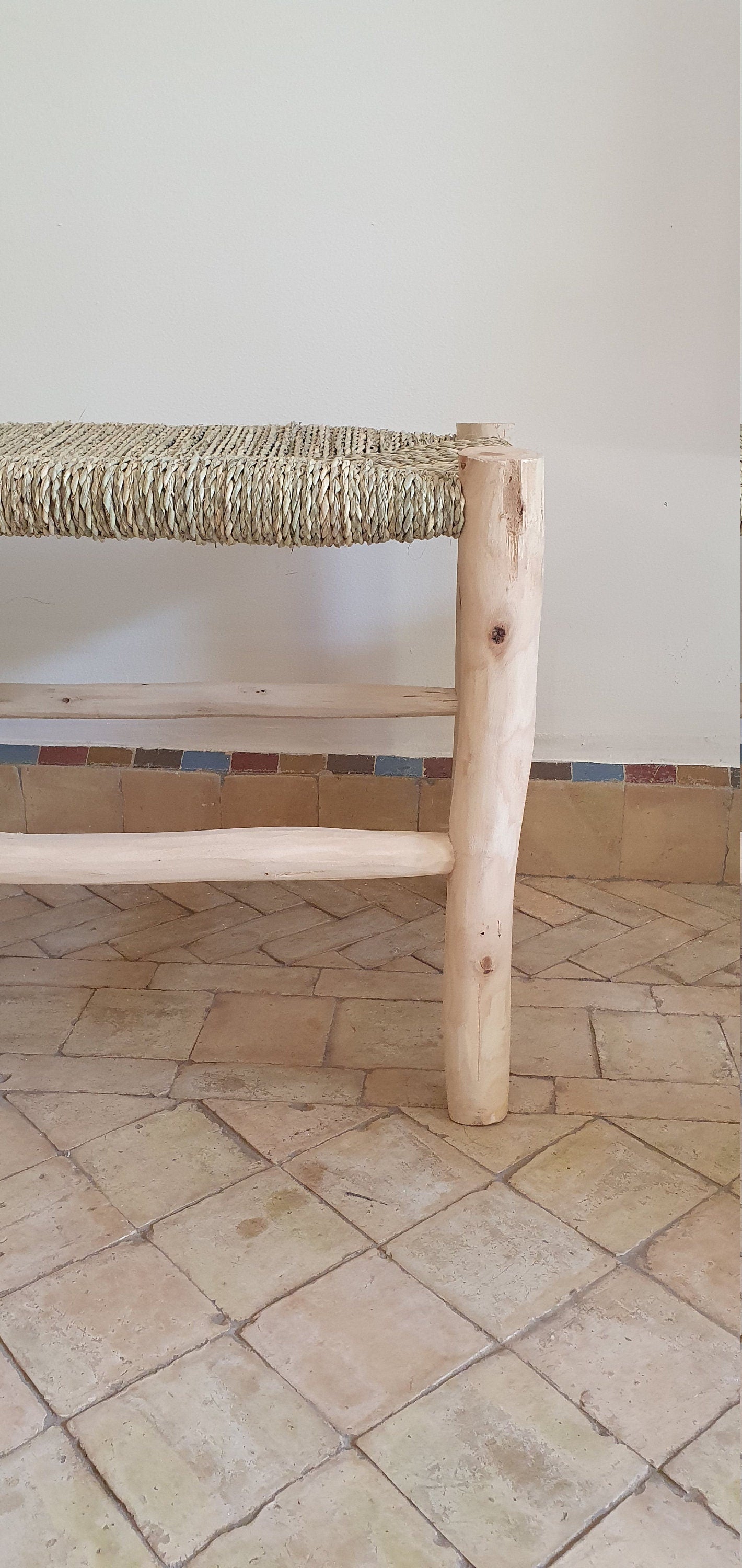 A side view of a rustic wooden bench featuring intricate natural weaving on the seat and backrest.