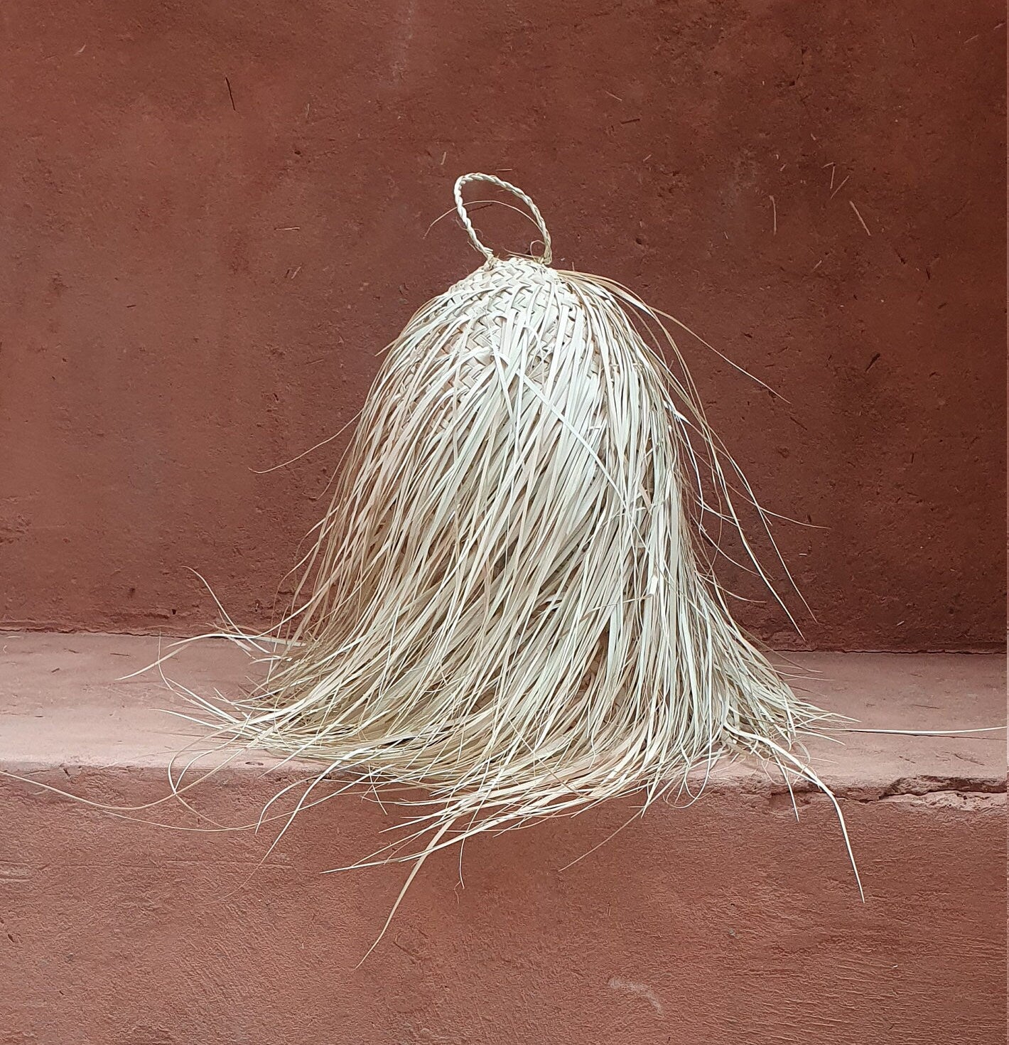Suspension artisanale en forme de cône en feuille de palmier.