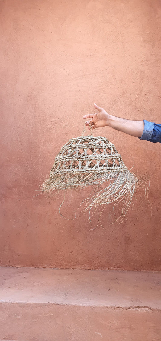 Suspension en paille en forme de boule ajourée avec détails en doum et cheveux d'ange.