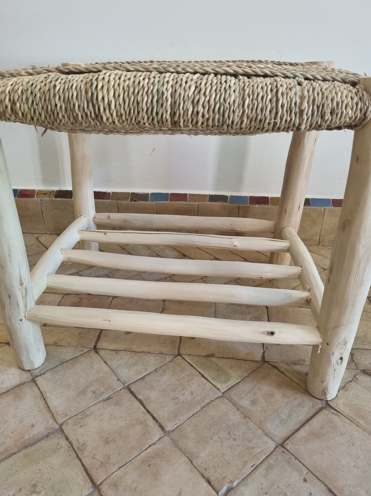 Un meuble en bois massif avec un banc orné d'un tressage naturel, apportant une touche d'authenticité à l'intérieur