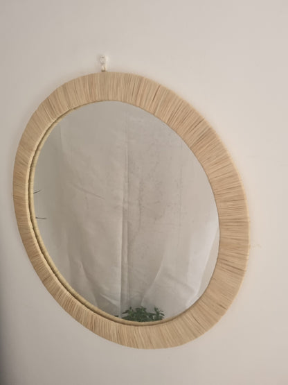 Miroir rond en raphia naturel au design circulaire.