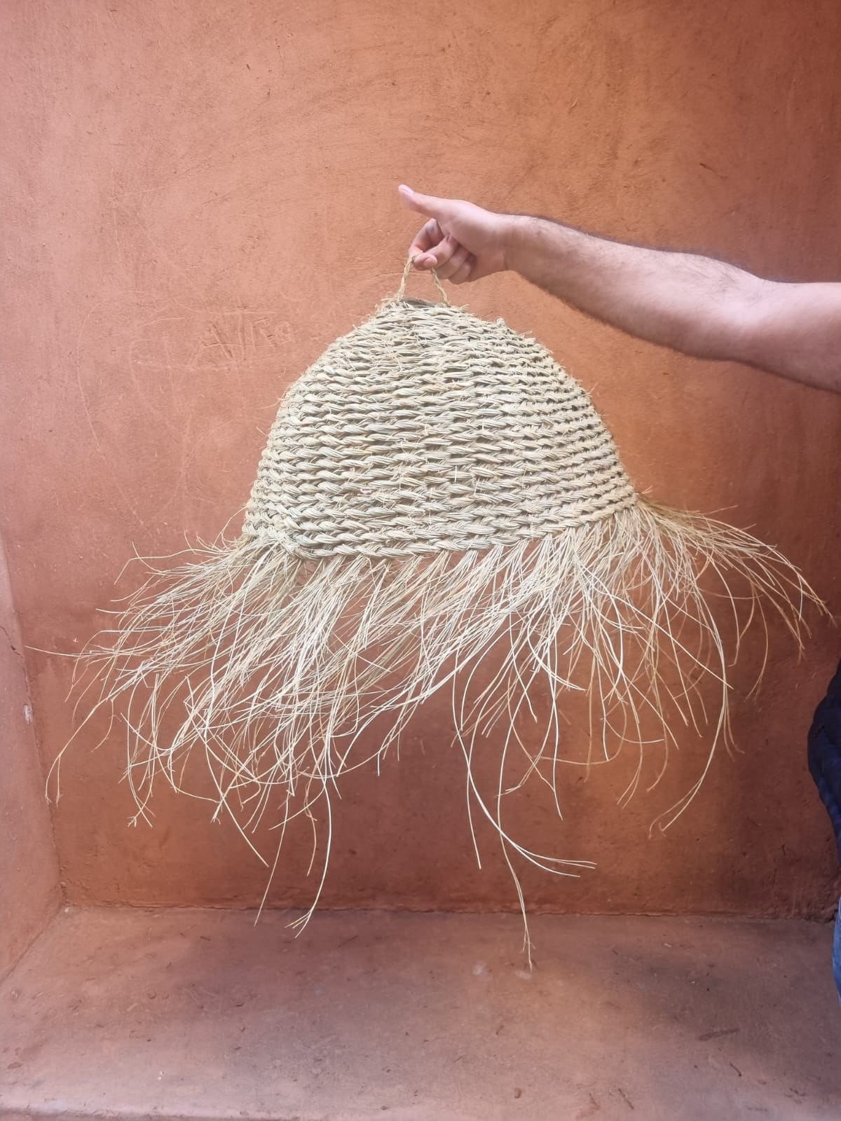 Image d'un parasol suspendu à franges avec une boule doum.